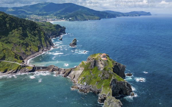 Drone shot, Aerial view of a rugged coastline with cliffs and a small island surrounded by blue ocean, San Juan de Gaztelugatxe, Basque Country, Spain