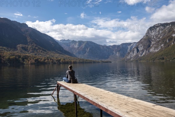 Sitting on a small jetty and enjoying the view on the landscape of lake Bohinj in the Triglav National Park, The Julian Alps, Slovenia