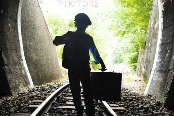 Child walking on railway road with vintage siutcase