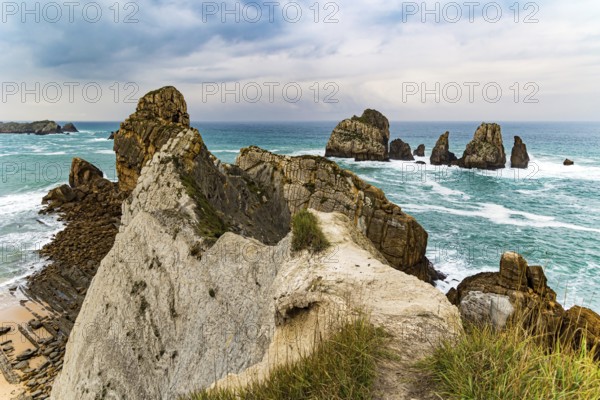 Picturesque cliffs and huge stones oppose the ocean. Spanish coast, Cantabria. Rocky coastline of the Atlantic Ocean. Stormy autumn day in the Bay of Biscay. Portio beach