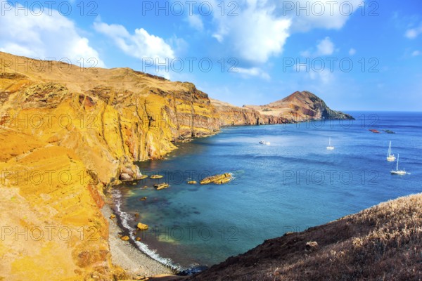 The west coast of the island of Madeira - the bay between the rocks with yachts and boats. Madeira is island in the Atlantic. The blinding sun. The concept of active, ecological and photo tourism