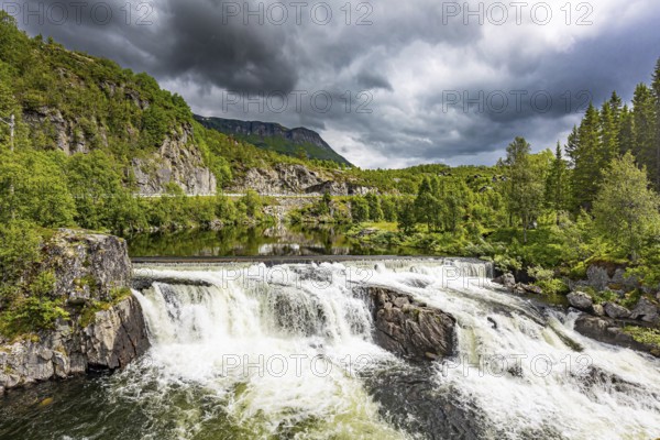 Magnificent seething waterfall - the threshold on the river Bioreio. The interesting trip to the Scandinavian Peninsula. The green shores are reflected in the smooth water