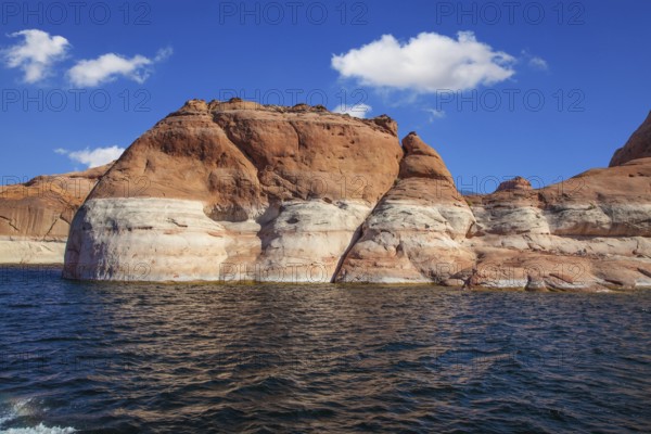 Picturesque artificial huge reservoir Powell on the river Colorado, USA. The lake is surrounded with picturesque coast from orange sandstone. Walk on the lake Powell on a sunset