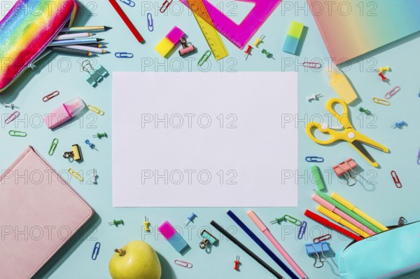 Creative student desk with empty white sheet and colorful modern school supplies on blue background. Top view. Flat lay. Copy space. Back to school concept