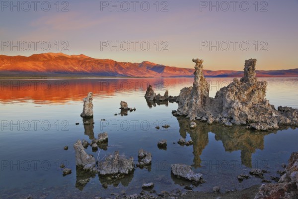 The magic of Mono Lake. Outliers -calcareous tufa formation on the smooth water of the lake. Orange sunset
