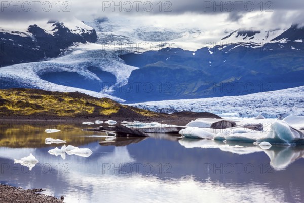 The grand glacier Vatnajokull is melting at the edges, sliding to the ocean. Glacier meltwater form a picturesque lake. Summer in Iceland. The concept of extreme northern tourism