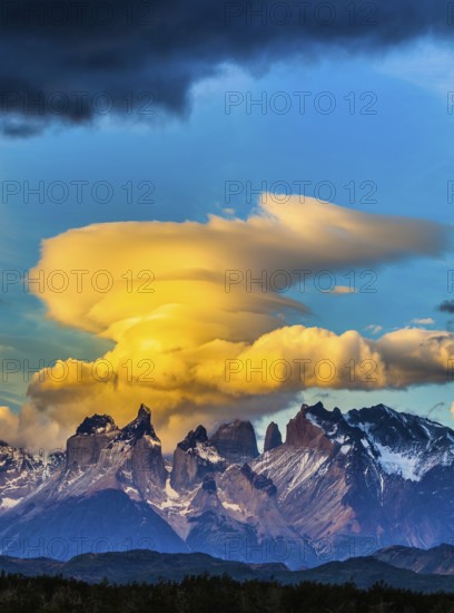 The black-and-steel color of the cliffs of Los Cuernos. Magnificent clouds in the rays of the sunset. The concept of extreme and active tourism. Torres del Paine National Park