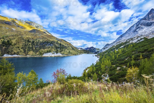 Glacial lake with clear cold water. Mountain Lake Lago di Fedaia, Dolomites. The magic and harmony of the Dolomites. The concept of ecological and extreme tourism