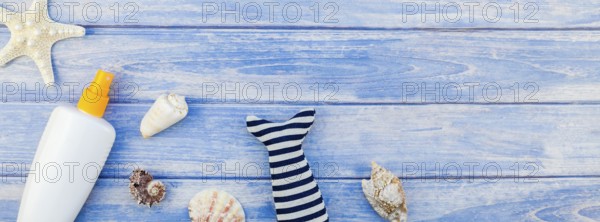 Long wide banner flat lay concept summer travel vacations. Top view of sunscreen bottle mockup seashells and starfish pastel blue wooden planks background copy space rustic style frame template text