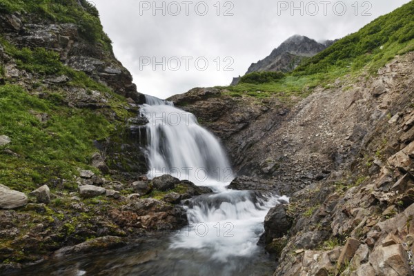 Summer mountain landscape of Kamchatka: beautiful view of picturesque waterfall in Mountain Range Vachkazhets. Eurasia, Russian Far East, Kamchatka Peninsula