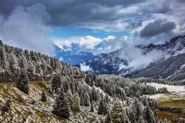 Heavy rain clouds flying over mountains. Evergreen forests in the valley covered with the first snow. The landscape of the Dolomites in snow