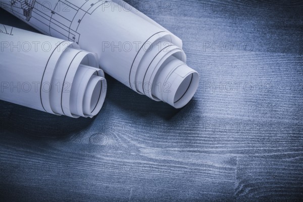 Rolled white blueprints on wood board