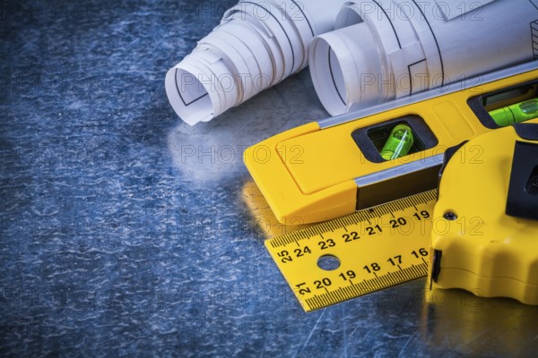 Ruler measuring tape construction level and blueprints on metallic scratched background building and architecture concept