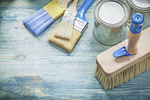 Paint cans brushes on wooden board top view construction concept