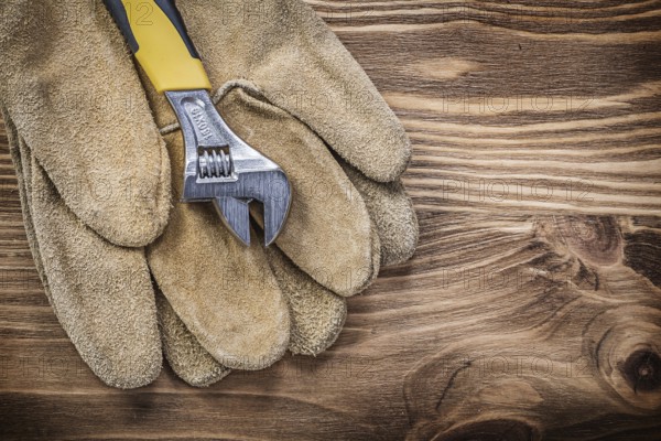 Safety gloves adjustable wrench on wooden board construction concept