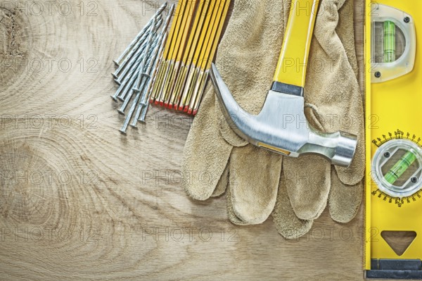 Construction level leather safety gloves wooden meter claw hammer nails on wood board building concept