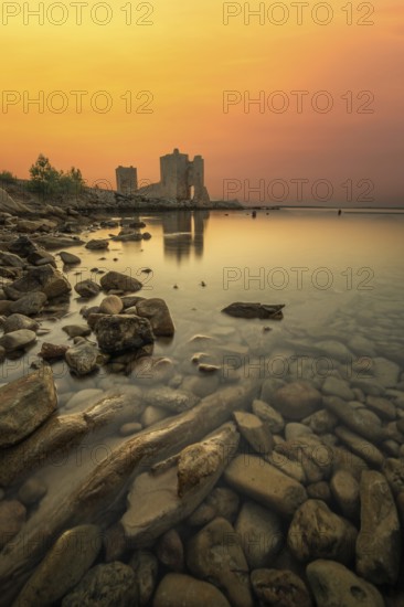 Castle ruins at dawn. Bay on the Mediterranean Sea with calm water at sunrise. Reflection of the sky and the Mediterranean landscape of Kastelina Castle, Vir Island, Zadar, Dalmatia, Croatia, Adriatic Sea