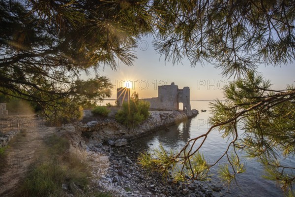 Sunrise on a rocky coast. Reflection in the calm water. Landscape shot of the restored remains of the Venetian fortress Kastelina on the Mediterranean Sea, Vir, Dalmatia, Croatia, Adriatic Sea