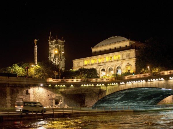 Illuminated bridge and historic building at night, reflected in the water of the river, paris, france