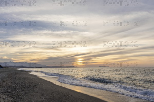 Beautiful coastline with a sandy beach and pebble beach at sunset. Beautiful sky colouring in the tourist and hotel area Platanes Beach, Rethymno, Crete, Greece