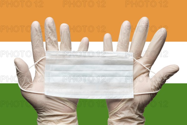 Paramedic holding face mask in two hands in white medical gloves on background flag of India. Concept coronavirus quarantine, pandemic outbreak, grippe, hygiene. Medical respiratory bandage for face