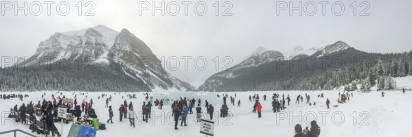 Lake Louise, Alberta, Canada. Jan 29, 2024. A panoramic scene capturing individuals engaged in ice skating on the frozen expanse of Lake Louise, framed by the majestic backdrop of the mountains