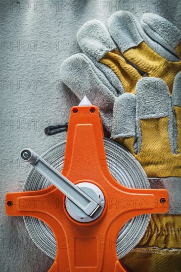 Pair of protective gloves measuring tape on concrete background