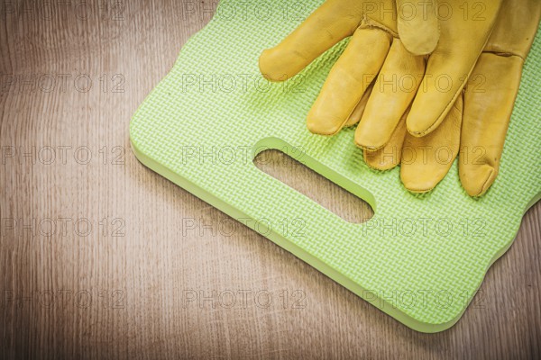 Protective gloves kneeling pad on wooden board gardening concept