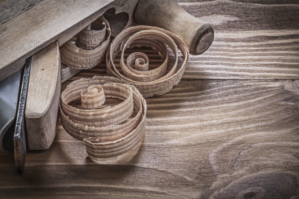 Shaving plane planning chips on vintage wooden board construction concept