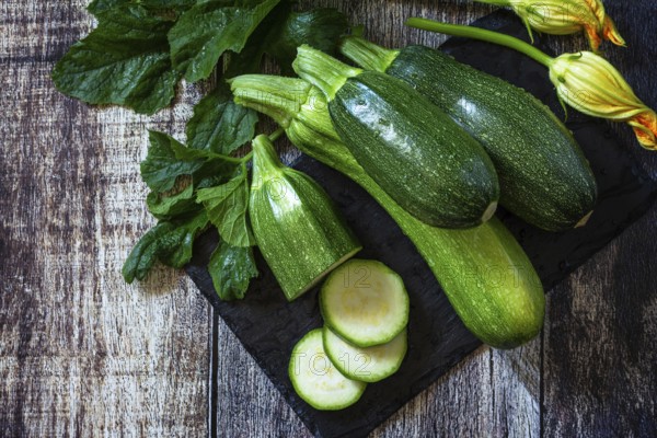 Harvesting zucchini. Healthy uncooked fresh green zucchini with slice on a wooden kitchen table. Top view flat lay background. Copy space