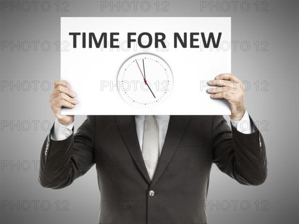 A business man holding a paper in front of his face with time for new and a clock