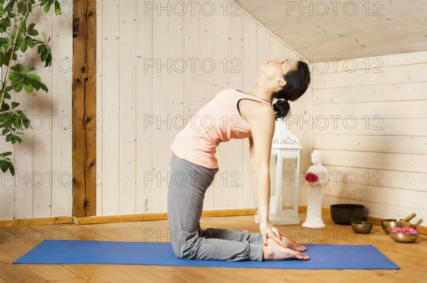 An image of a pretty woman doing yoga at home - Ushtrasana