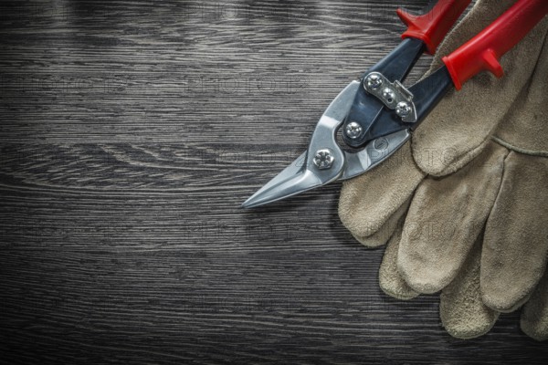 Pair of protective gloves steel cutter on wooden board