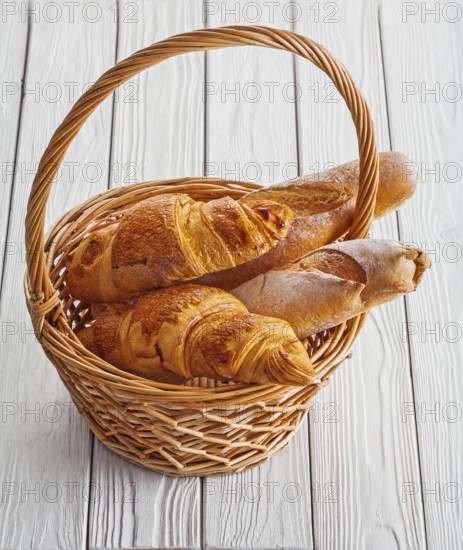 View baguettes and croissants in wicker basket on white boards