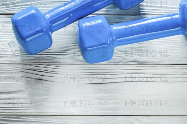 Pair of dumbbell weights on wooden board sports training concept
