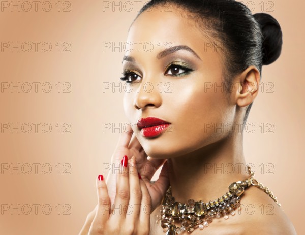 Upscale Indian woman wearing gold jewellery and red lipstick on beige background, Toronto, Canada