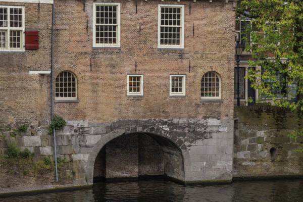 Brick wall with several windows and a large arch leading into the water, Rotterdam, Netherlands