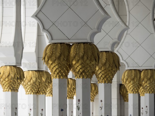 Decorative white columns with golden ornaments in a mosque, detail view, white mosque with towers and domes and gilded columns, Abu Dhabi, Arab Emirates