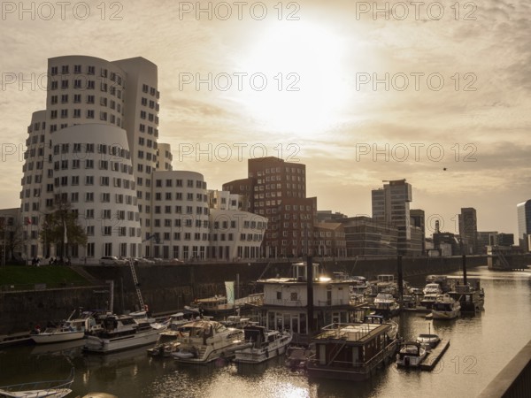 Harbour with boats in the foreground and modern skyscrapers in the background at sunset, Düsseldorf, North Rhine-Westphalia, Germany