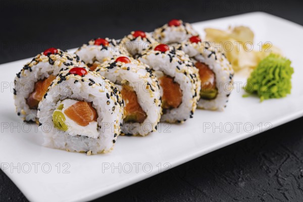 Food, Delicious sushi rolls with salmon, avocado, and sesame seeds served on a sleek plate, garnished with wasabi and ginger