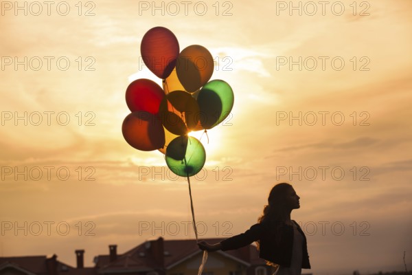 Pretty girl with big colorful balloons walking on the hills near the town. Focus on balloons