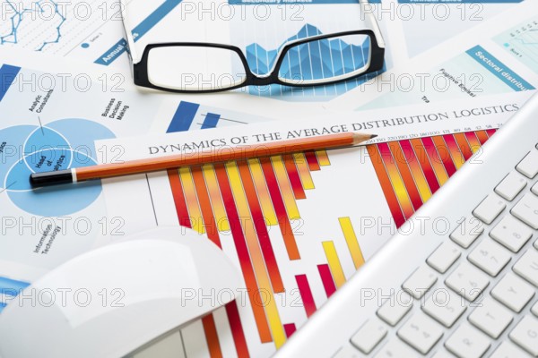 Business workplace with keyboard glasses and financial documents on table