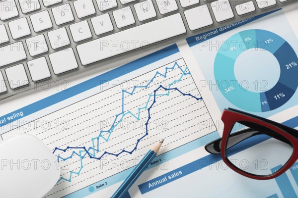 Business workplace with keyboard mouse and papers with graphs and diagrams