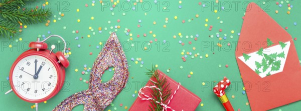 New Year or Christmas pattern flat lay top view with red alarm clock twelve midnight fir tree branch Xmas holiday celebration green paper bright colorful confetti background. Long wide banner 2020