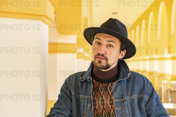 Portrait of a stylish handsome young man with a scarf outdoors. A serious man wearing a hat and a jaket looking confident at the camera