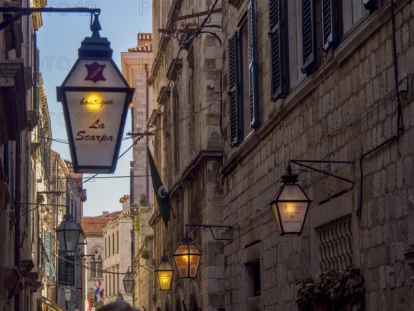 Street at night with illuminated lanterns and various shop signs in front of old buildings, dubrovnik, Mediterranean Sea, Croatia