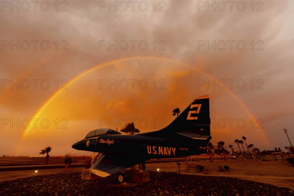 Dawn at Naval Air Field El Centro, CA: Sunlight paints vibrant hues across the sky, casting a mesmerizing rainbow over parked aircraft, creating a breathtaking spectacle