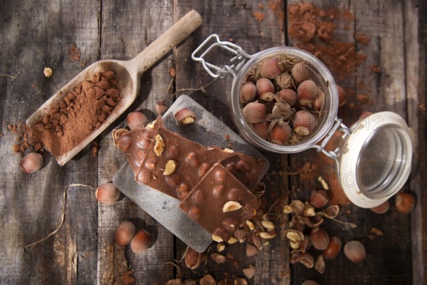Pieces of milk chocolate with hazelnuts on wooden table