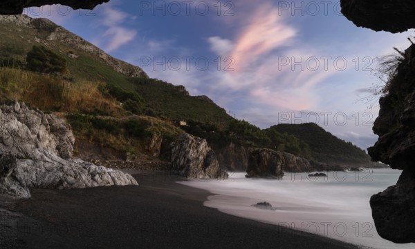 Silhouette frame of a beach cave and view Marina di Maratea Beach at sunset