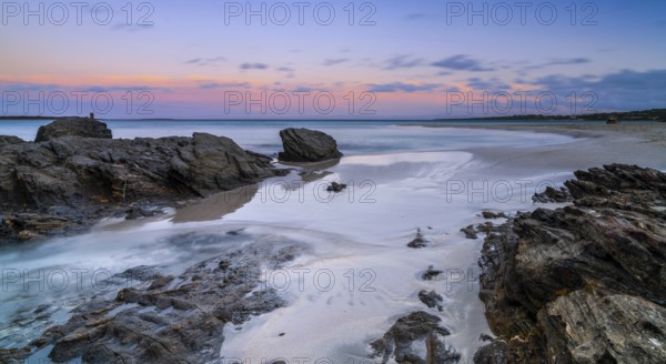 Colorful sunset over the picturesque white sand beach and turquoise waters at La Pelosa Beach